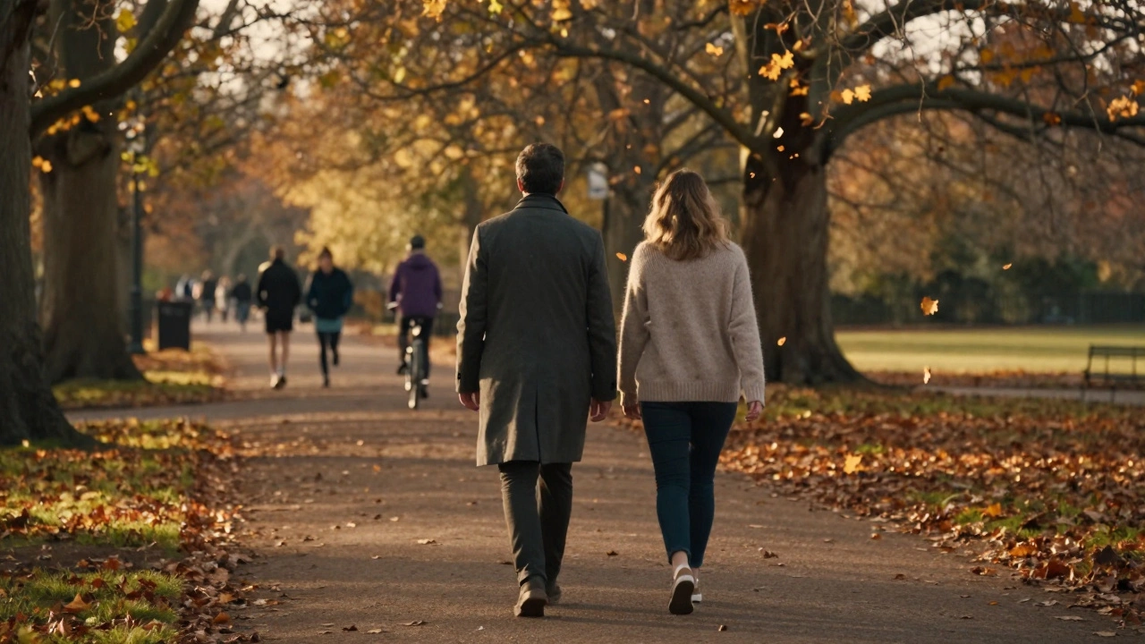 A couple walking hand in hand through Hyde Park during autumn golden hour.