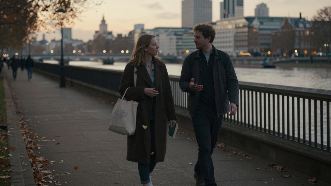 Two people walking peacefully along a riverside path in London at golden hour.